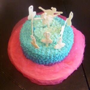 white chocolate ballerina cake. a pink and blue cake is topped with white chocolate ballerinas topped with edible glitter.