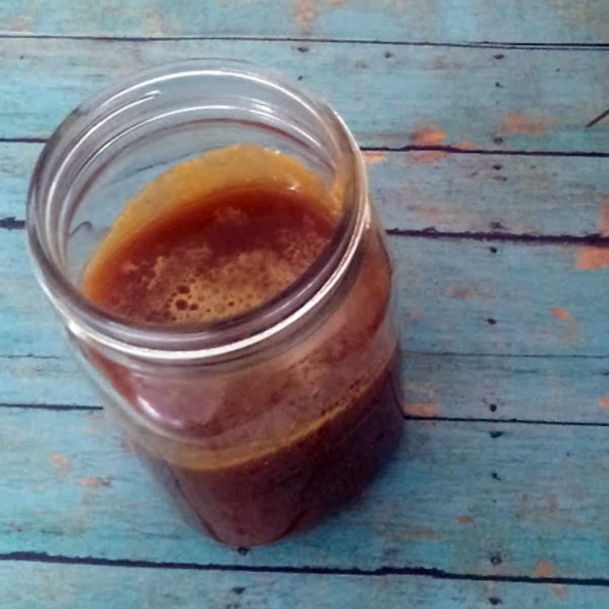 a brown and bubbly salted caramel sauce recipe is in a mason jar. 