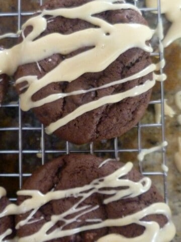A close-up photo of a double chocolate salted caramel cookie. The cookie is made with a soft and chewy chocolate cookie base and topped with a generous drizzle of salted caramel sauce and a sprinkle of sea salt.