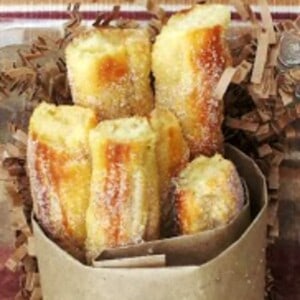 a picture of baked churros with a crisp exterior and light and airy interior. The baked churros are wrapped in brown parchment paper and tossed in a cinnamon sugar coating.