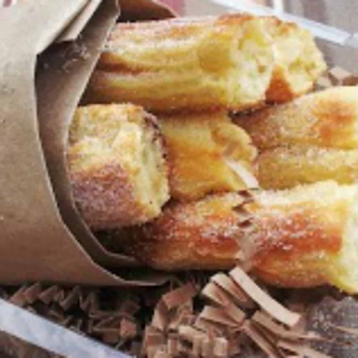 oven churros have a crisp exterior and light and airy interior . they are coated in a cinnamon sugar mixture and wrapped in brown parchment paper. 