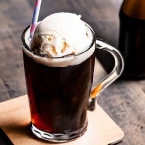 The image shows a glass of root beer with a scoop of vanilla ice cream and vanilla syrup