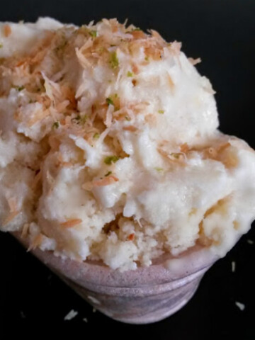 A bowl of creamy Coconut Pineapple Lime Ice Cream garnished with shredded coconut.