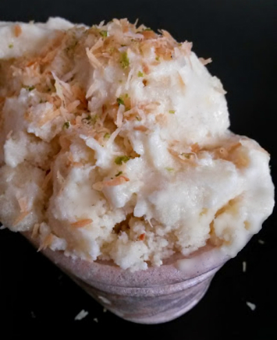 A bowl of creamy Coconut Pineapple Lime Ice Cream garnished with shredded coconut.