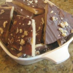 A bowl of English toffee, which is a traditional British sweet treat made with sugar, butter, and chocolate. The toffee is covered in chocolate and broken into bite-sized pieces.