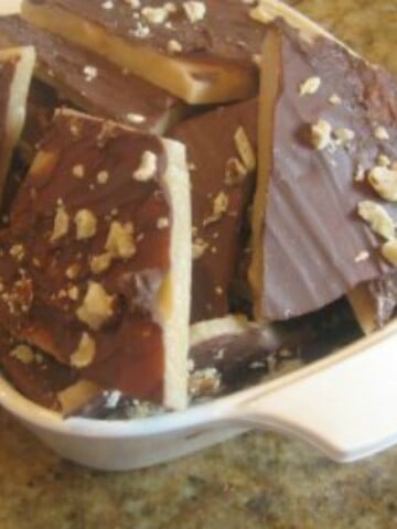 A bowl of English toffee, which is a traditional British sweet treat made with sugar, butter, and chocolate. The toffee is covered in chocolate and broken into bite-sized pieces.
