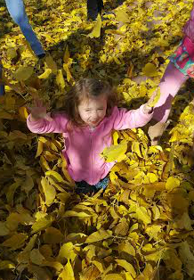 kid playing in leaves