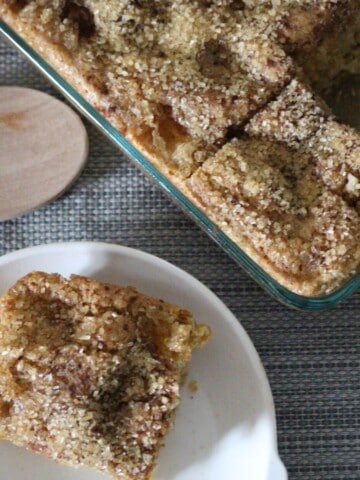 a photo of a slice of peach snickerdoodle dessert bars. The top of the bars have sprinkled sugar on top and juicy fresh peaches inside.