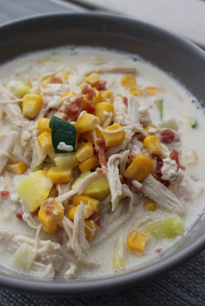 This image shows a delicious bowl of summer corn chowder. The chowder is made with fresh corn, potatoes, cream, and milk. It is a light and refreshing soup that is perfect for summer. The fresh chives add a pop of flavor and color.