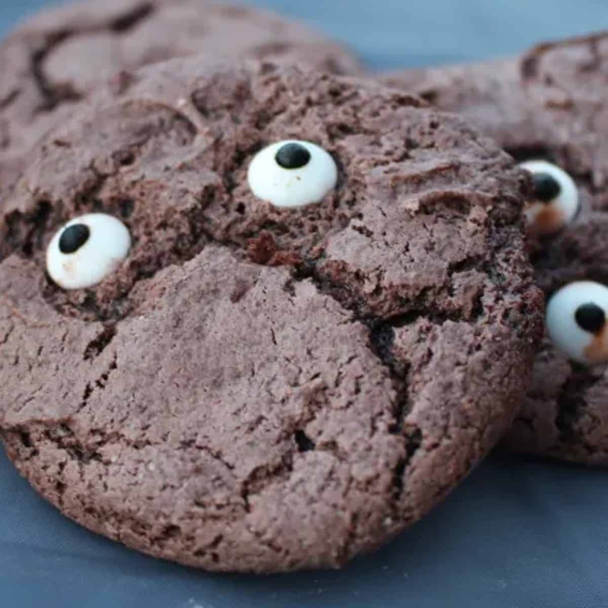A rustic wooden table spread with a variety of monster eye cookies, each with its own unique personality and googly eye expression