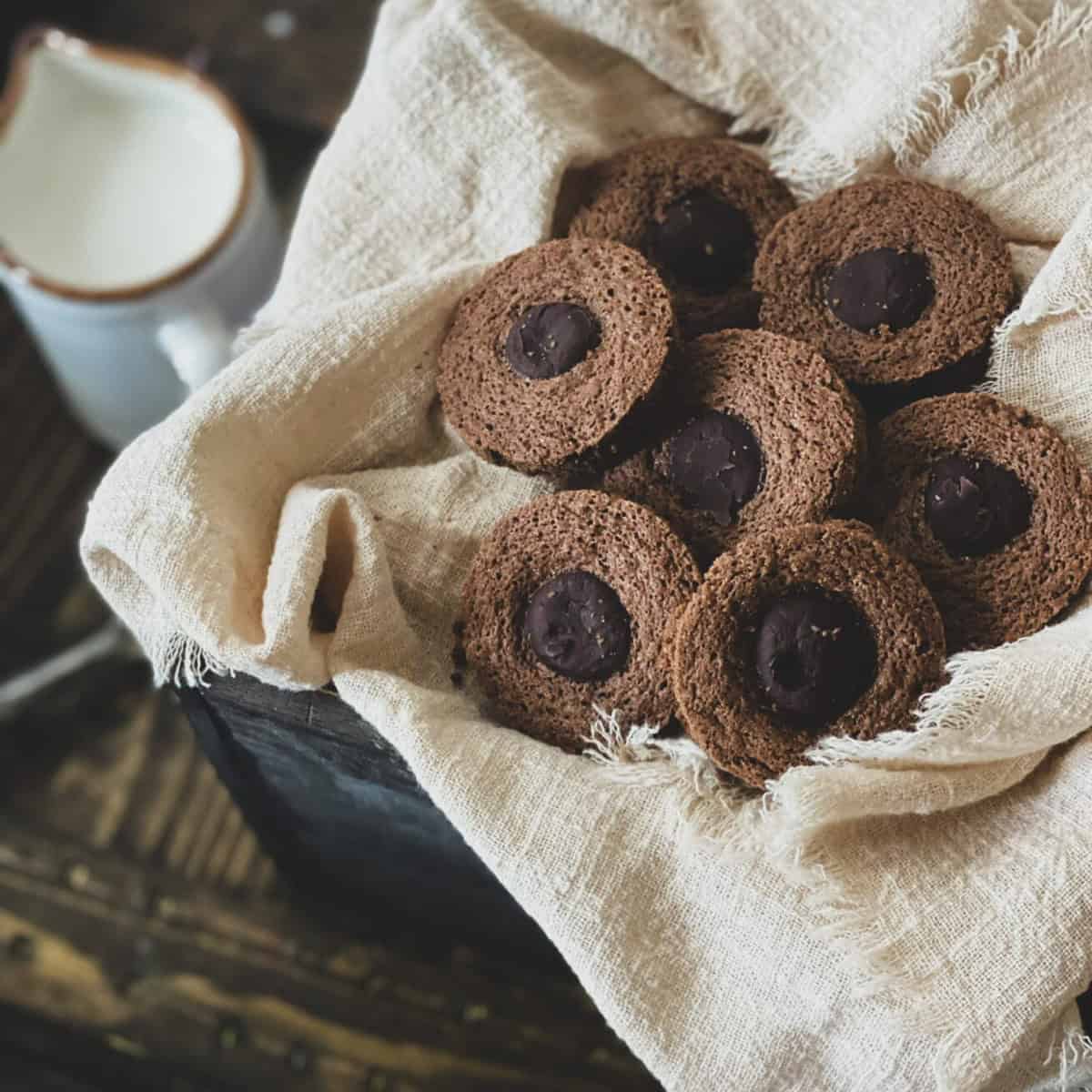 a basket of chocolate caramel cookies with a rolo caramel placed in the center of each cookie. the picture describes a rolo cookies recipe.
