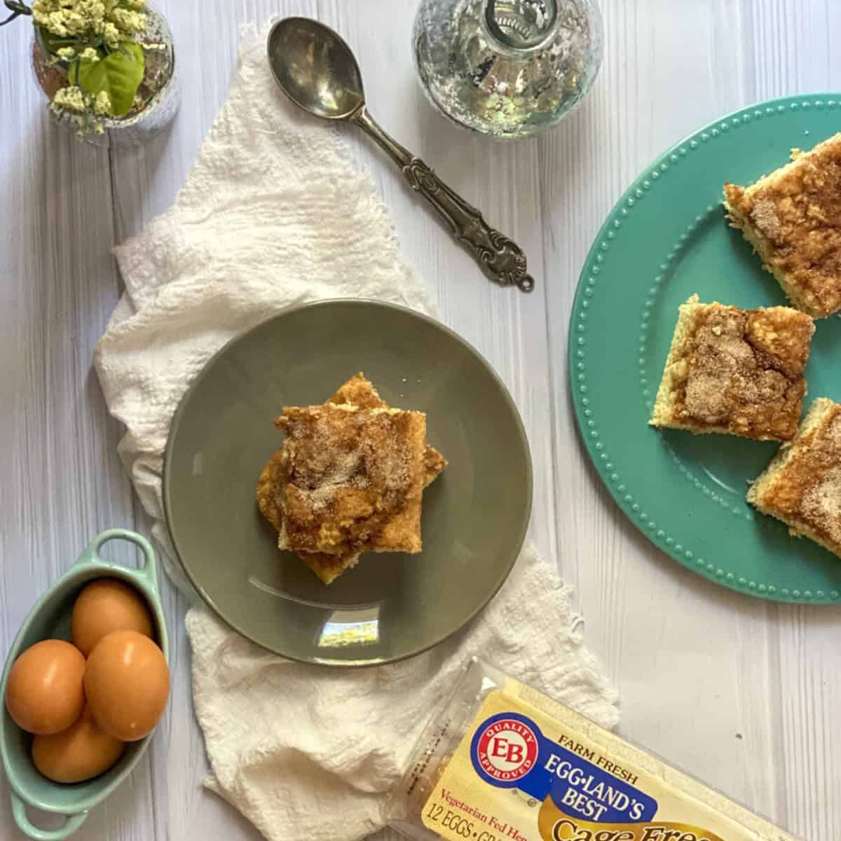 Snickerdoodle biscuits sheet pan breakfast is a baked good that typically has a crumbly coffee cake-like texture with swirls of cinnamon sugar throughout and a cinnamon sugar streusel topping. The breakfast is made with Eggland's best eggs which are featured in the photo. 