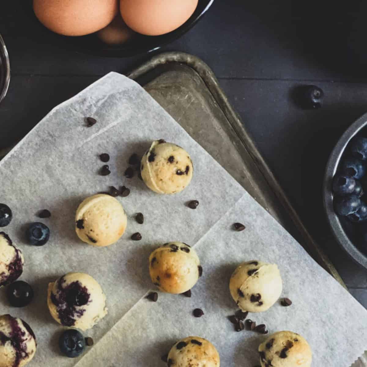 A tray of blueberry pancake bites recipe with chocolate chips on a wooden table.