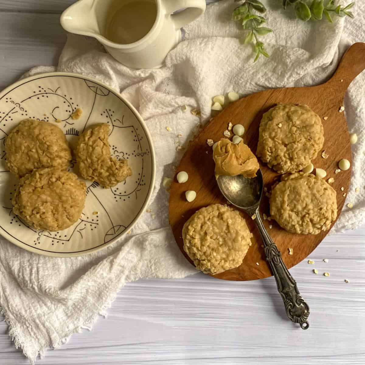 These look like delicious white chocolate peanut butter oatmeal cookies! They have a golden brown, chewy appearance and are generously sprinkled with white chocolate chips. There's a spoonful of peanut butter on the side, hinting at the rich flavor of these cookies.