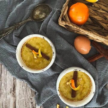 A creamy and smooth dairy-free version of crema catalana dessert. It features a caramelized sugar crust on top, with a rich and velvety custard-like filling underneath. The dessert is beautifully presented in a ramekin, garnished with a cinnamon stick and lemon and orange zest ribbon