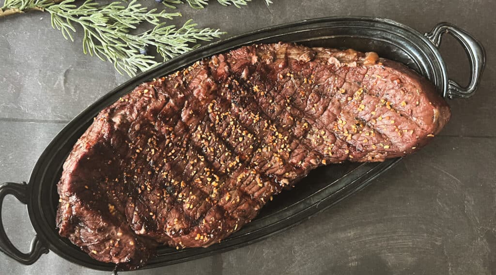 a beautifully grilled london grill recipe. the steak has a rub on it and is served on a platter.