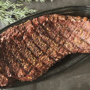 a beautifully grilled london grill recipe. the steak has a rub on it and is served on a platter.