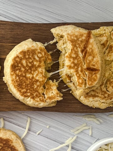 A plate of pupusas, a traditional Salvadoran dish. The pupusas are made of thick corn tortillas filled with cheese, beans, and pork. They are golden brown and slightly crispy on the edges. The cheese is melted and gooey, and the beans are hearty and flavorful.