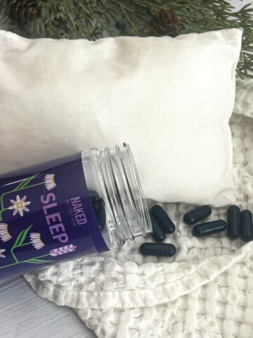 a picture of naked nutrition natural sleep supplement. A picture of a pillow and blanket are shown. A bottle with flowers is shown. There are purple pill capsules shown in the photo.