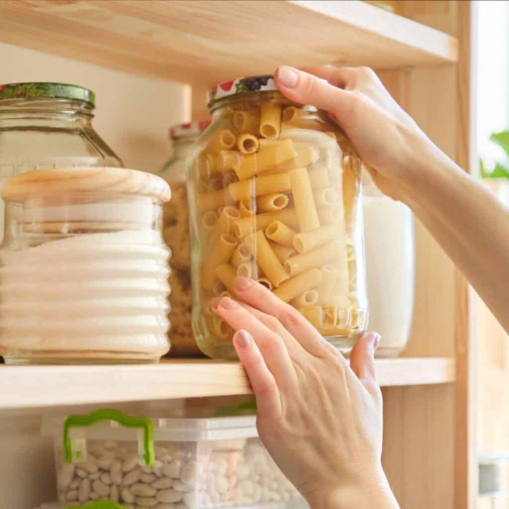 a picture of an organized pantry with items placed in large glass jars for easy visibility. 