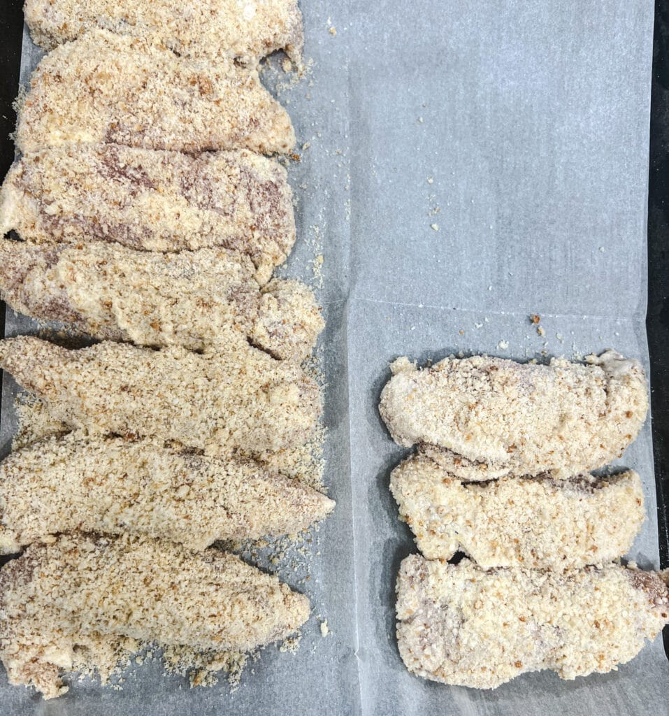 breaded chicken breasts on a baking tray. 