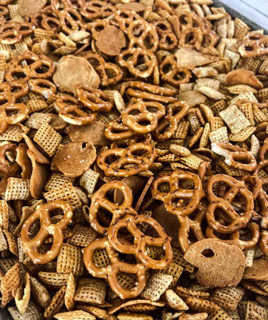 homemade chex mix is ready to bake on a metal baking sheet. 