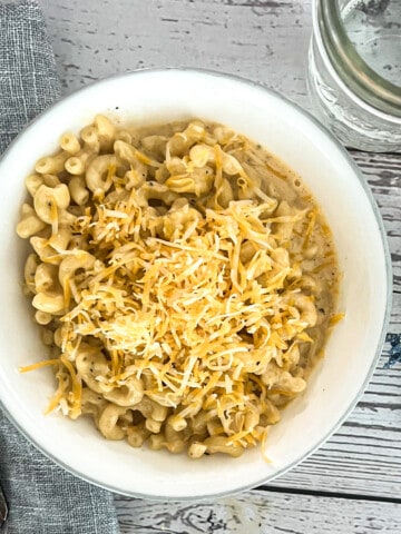 A bowl of macaroni and cheese with a creamy cheddar cheese sauce and a sprinkling of paprika. The macaroni is elbow macaroni, and the cheese sauce is made with cheddar cheese, milk, butter, and flour. The paprika is sprinkled on top for garnish. This image could be used to illustrate a blog post about noodles and company copycat wisconsin mac and cheese.