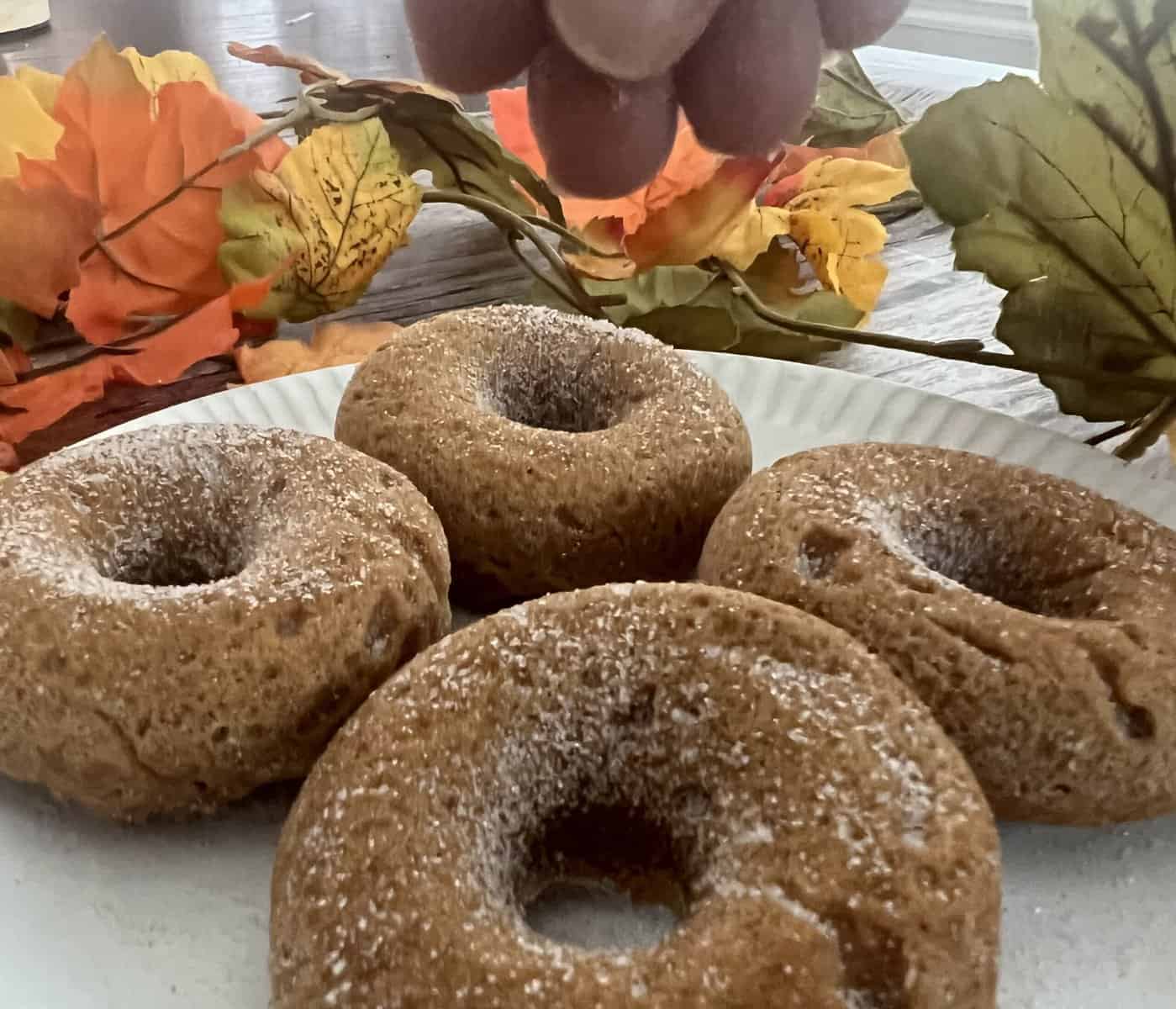 a photo of pumpkin spice and sugar being sprinkled over a pumpkin spice donut