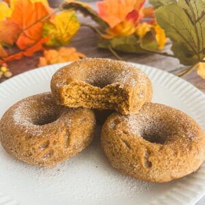 Three pumpkin spice donuts on a plate, topped with sugar and pumpkin spice seasoning