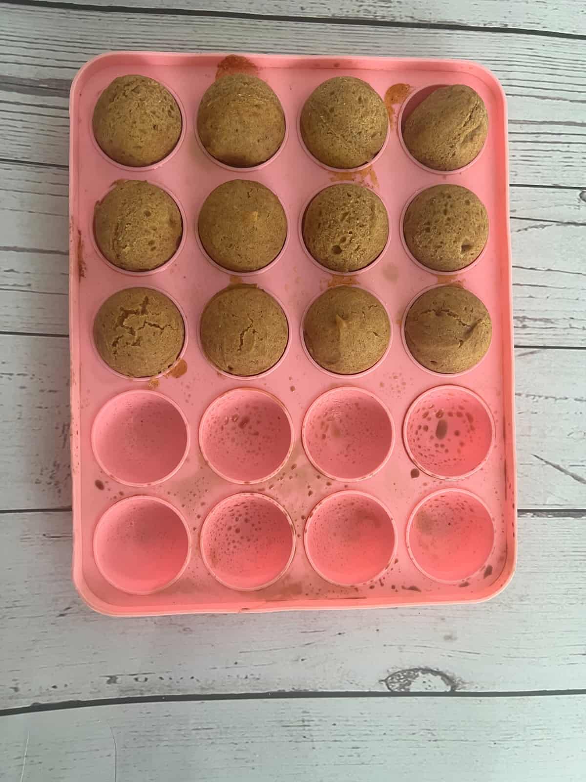 a photo of a pink cake pop pan with pumpkin spice cake mix inside. The cake pop pan is perfect for making donut holes. 