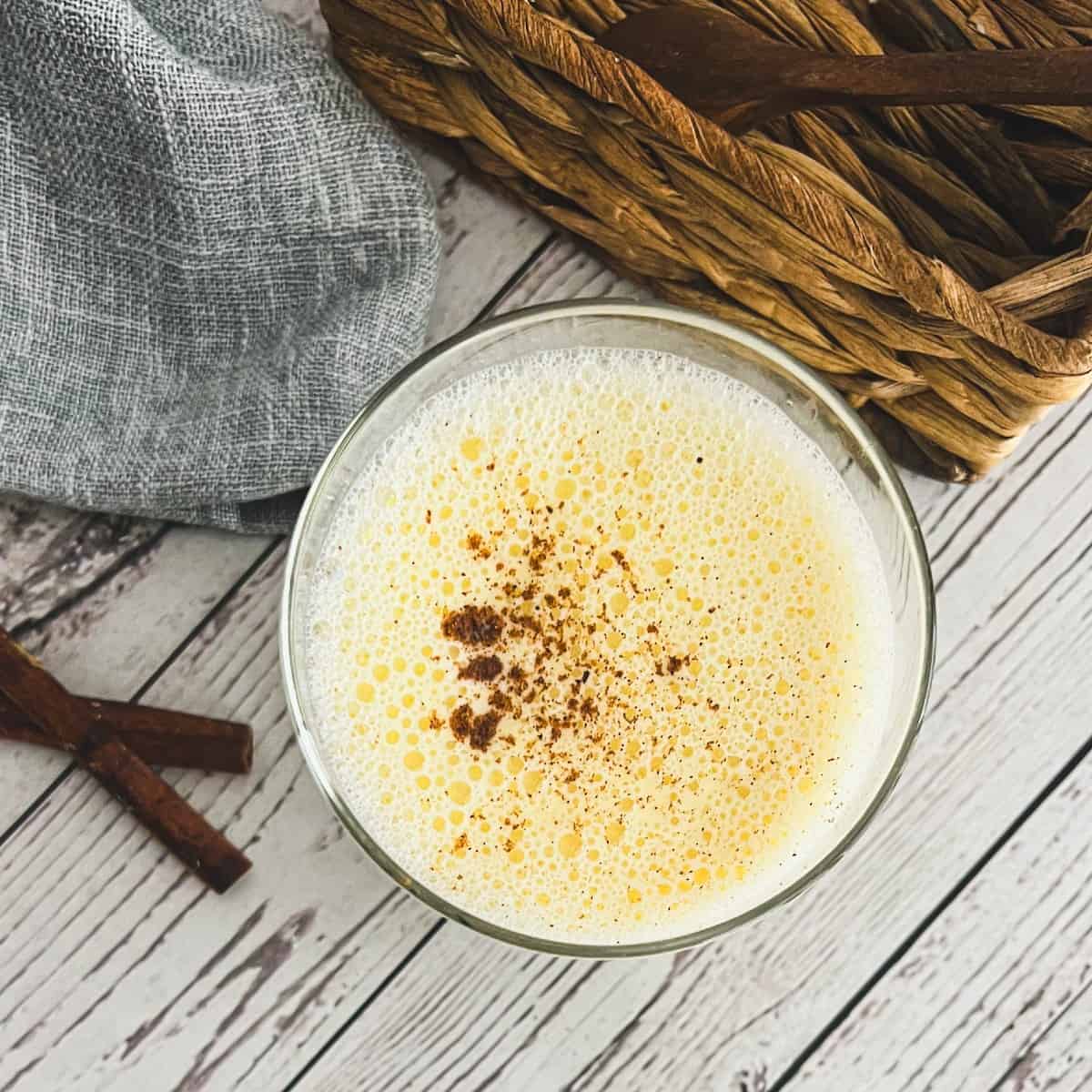 A festive glass of dairy-free eggnog, topped with whipped coconut cream and a sprinkle of cinnamon. Pure holiday cheer, without the dairy!