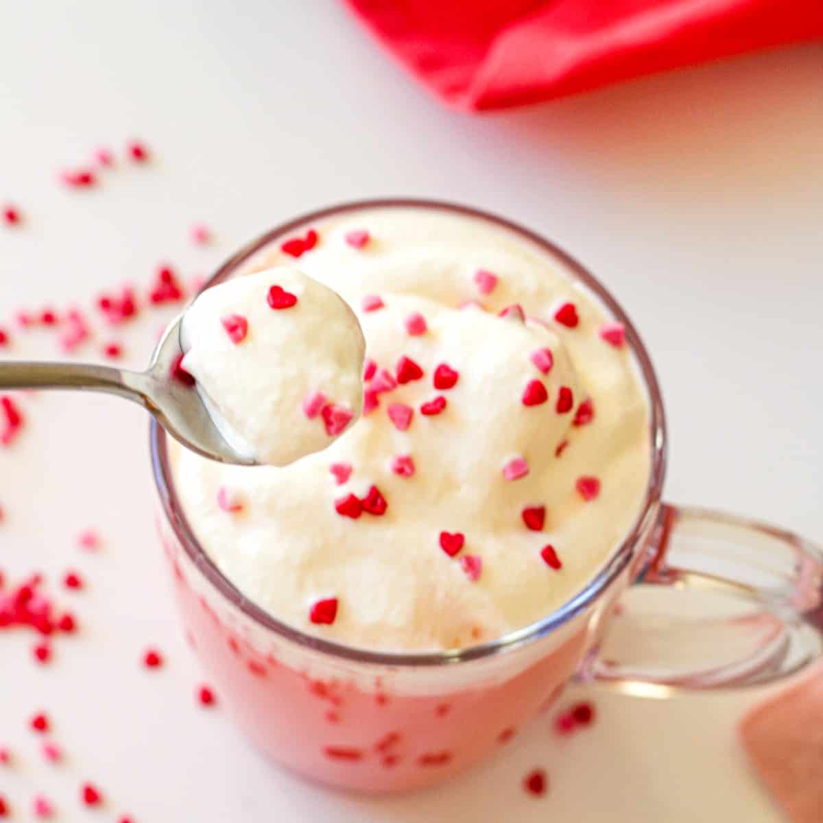 a picture of red velvet hot cocoa topped with whipped cream and sprinkles