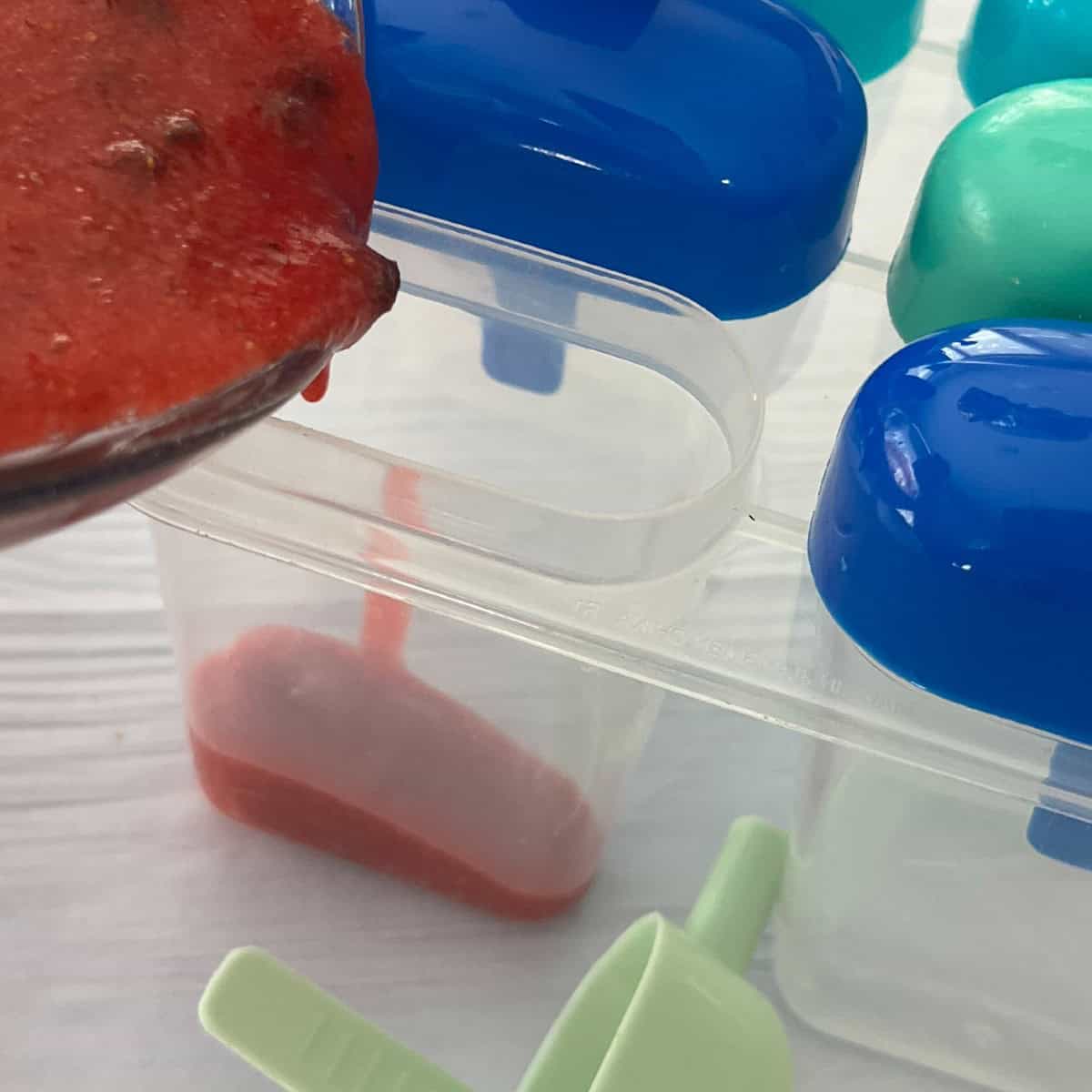 pour strawberries into popsicle mold