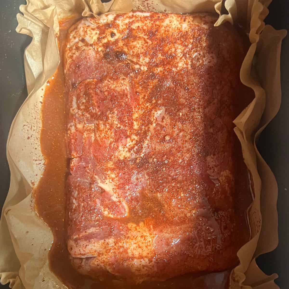 a photo of a pork roast covered in taco seasoning. The pork roast is sitting in a slow cooker