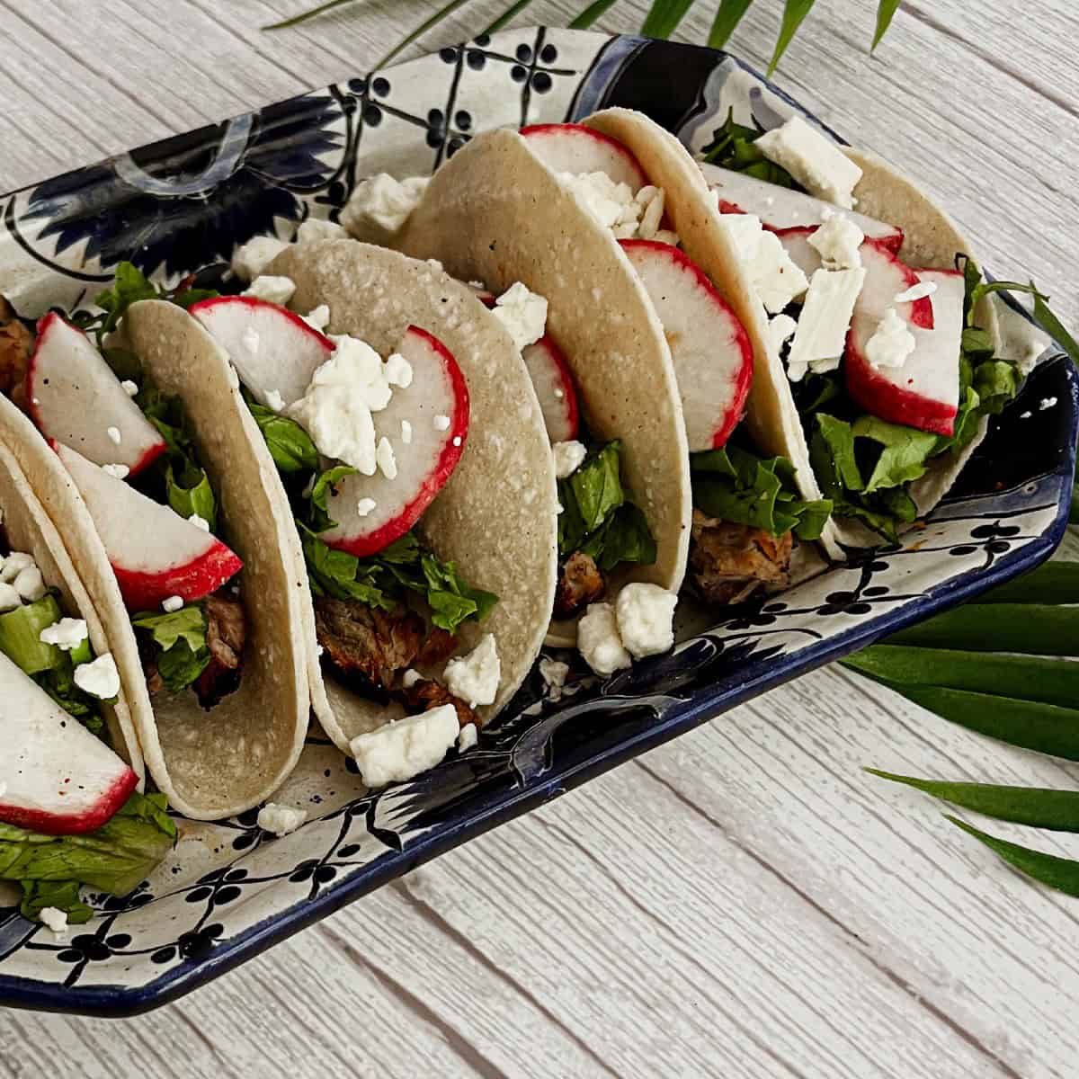 a photo of pork tacos filled with radishes, shredded pork and cotija cheese